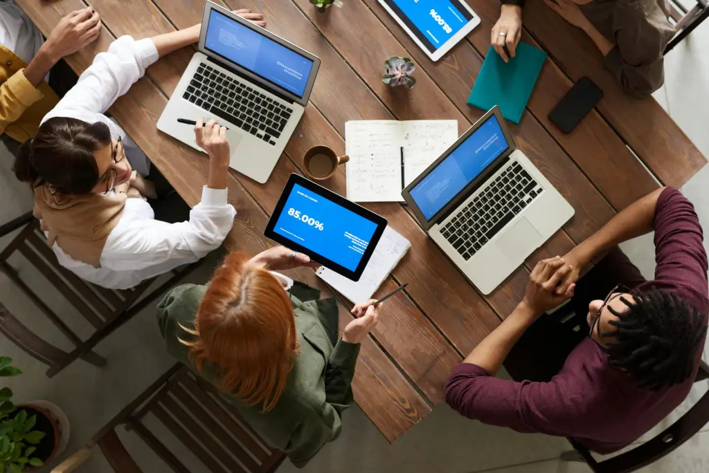 People sitting around a table with laptops and notebooks