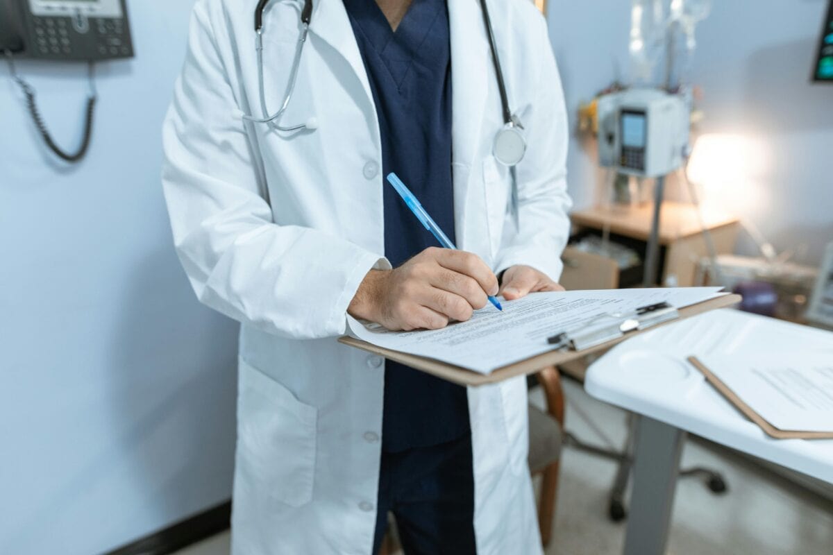 Hospital provider writing on clipboard.