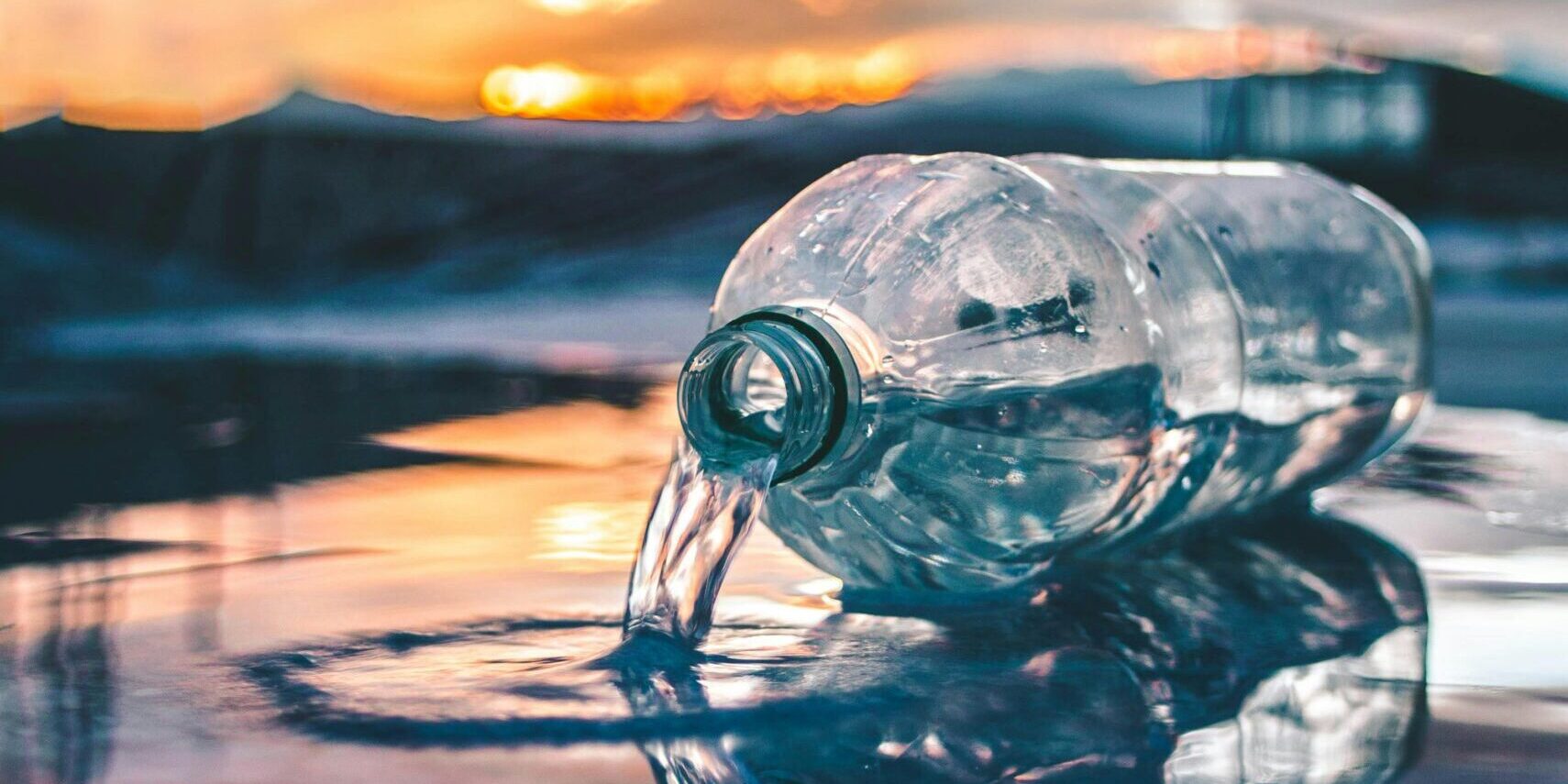 Water bottle on its side leaking water onto the ground.
